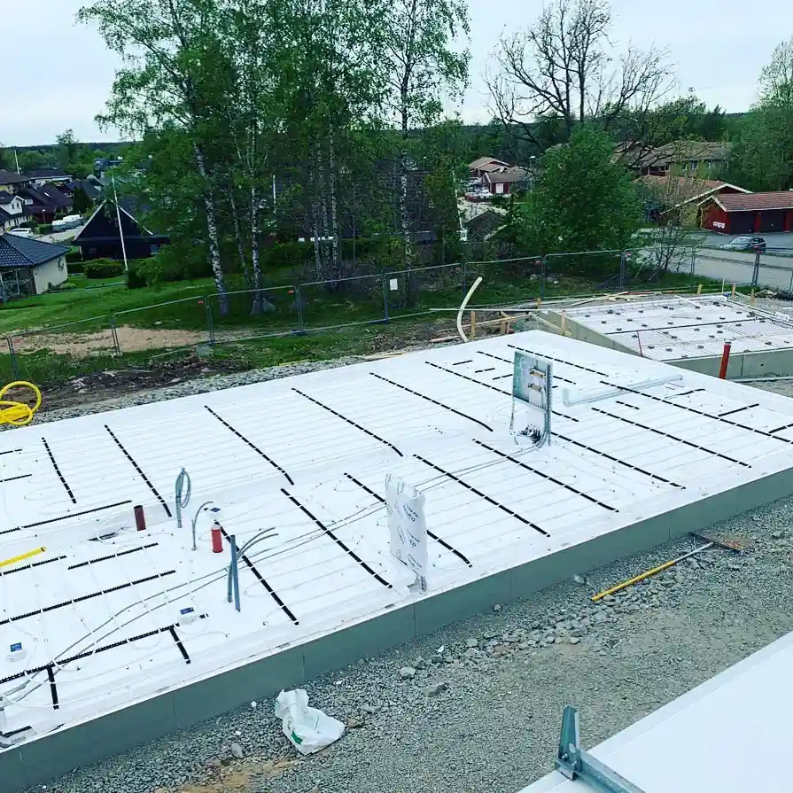 Byggarbetsplats med grundplattor och synliga installationer