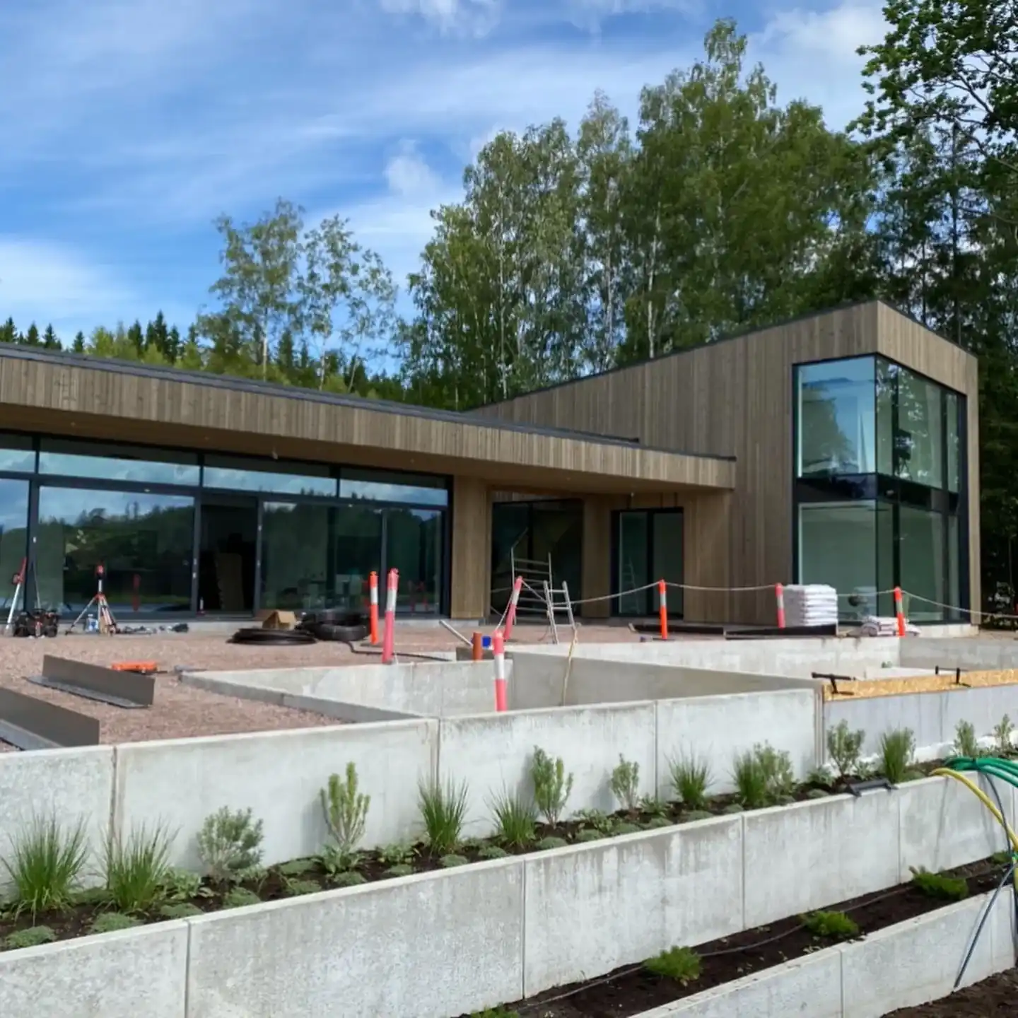 Modernt trähus med stora glasfönster och planteringar