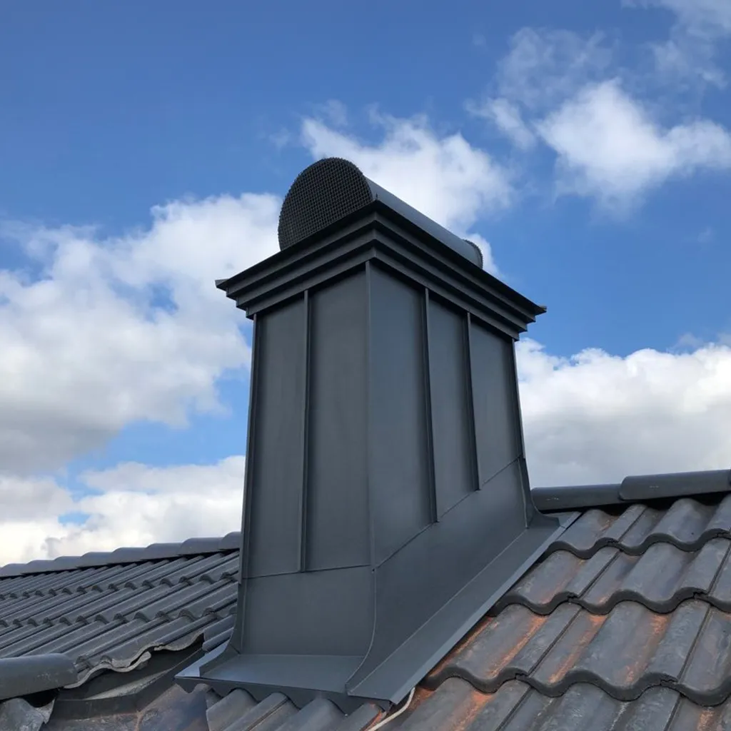 Plåtklädd skorsten mot blå himmel